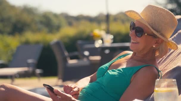 Oudere Gepensioneerde Vrouw Zwemkleding Zonnehoed Zonnebril Ontspannen Bij Het Zwembad — Stockvideo