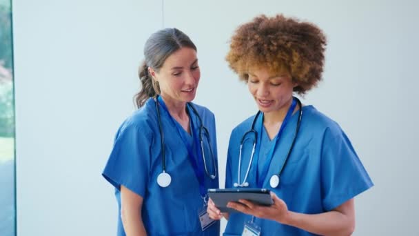Two Female Doctors Wearing Scrubs Digital Tablet Discussing Patient Notes — Stock Video