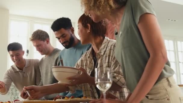 Groep Van Vrienden Thuis Keuken Toevoegen Toppings Aan Zelfgemaakte Pizza — Stockvideo