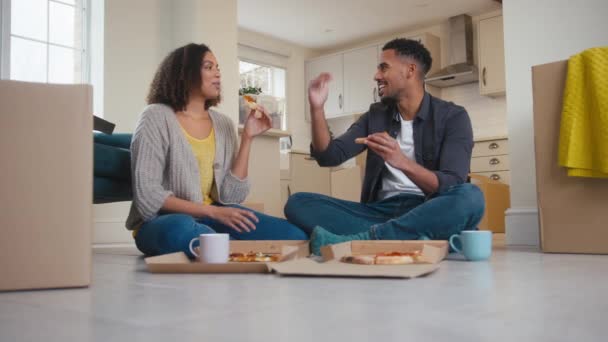 夫妻二人坐在地板上 一边吃着外卖比萨饼 一边在新家包装盒子 一边慢吞吞地走来走去 — 图库视频影像