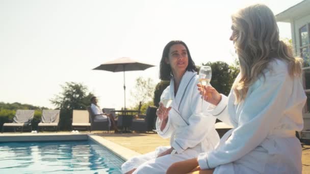 Twee Volwassen Vrouwelijke Vrienden Badjassen Buiten Bij Het Zwembad Champagne — Stockvideo
