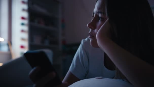 抑圧された十代の少女は 携帯電話でいじめのメッセージを見ている自宅でベッドに横たわる スローモーションで撮影 — ストック動画