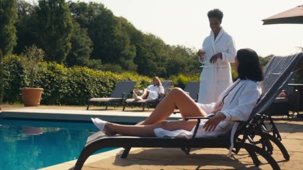 Mature Woman Wearing Robe Joins Friend Lying Outdoors Lounger Swimming — Wideo stockowe