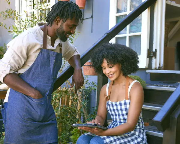 stock image Male And Female Staff With Digital Tablet Sitting On Steps Working In Garden Centre