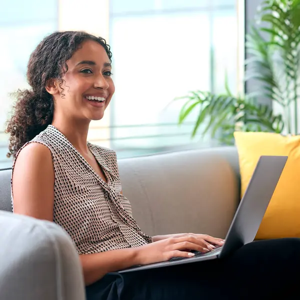 stock image Businesswoman Sitting In Lobby Of Modern Office Building Working On Laptop