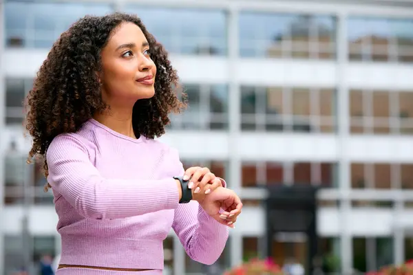 stock image Woman Wearing Fitness Clothing Sitting Outdoors Checking App On Fitness Monitor Or Smart Watch