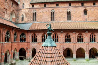Malbork kuyusu olan bir kale avlusu. Nogat nehrinin yanındaki Malbork 'taki Tötonik Düzen Kalesi. Polonya. Yeşillik tuğla işi. Pencereli büyük tuğla kale duvarı