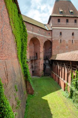 Nogat nehrinin yanındaki Malbork 'taki Tötonik Düzen Kalesi. Polonya. Kalenin giriş grubu ahşap bir köprüden geçiyor. Dikey biçim.