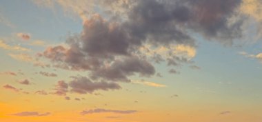 Pastel bulutlar güneş doğarken gökyüzünde. Gökyüzü klasik tarzda bulutlarla kaplı. Yatay fotoğraf. Günbatımının muhteşem arka planında yumuşak renkli bulutlar var. Panoramik.