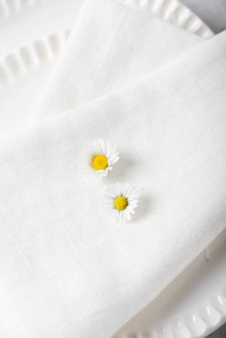 Vahşi papatya çiçekleri ve beyaz keten peçeteli rahat masa dekoru kavramı, seçici odak resmi