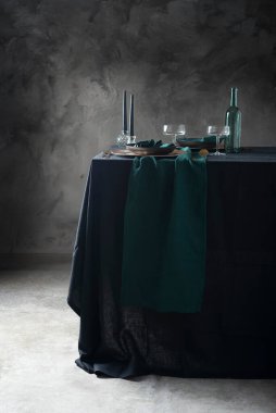 Koyu keten masa örtüsü ve yeşil koşucu ve seçici odak resmine sahip masa stili dekorasyonu