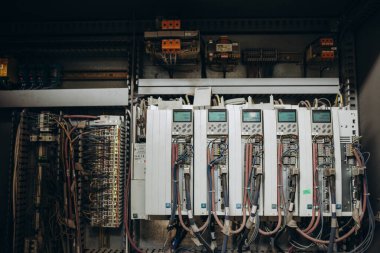 Elektrik mühendisi ana güç dağıtım panosundaki elektrik akımı voltajını kontrol etmek için dijital çoklu metre ölçüm ekipmanı kullanıyor..