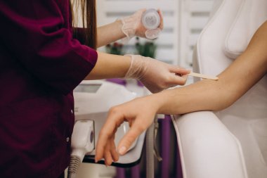 Güzellik uzmanı, güzel kadın elinin kıllarını lazerle alıyor. Ellerinde saç kesimi, klinikte lazer prosedürü.