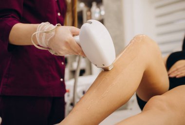 Kuaförde saçlarını aldırırken kadının mükemmel bacakları. Profesyonel güzellik uzmanı ya da kozmetikçi özel merhem ve teçhizat kullanır. yumuşak ve pürüzsüz bacaklı kılsız ten