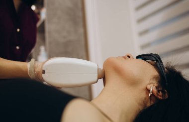 Elos epilasyon tüy çıkarma prosedürü bir kadının yüzünde. Güzellik uzmanı güzellik salonunda boynu lazerle gençleştiriyor. Yüz bakımı. Donanım ipl kozmetolojisi