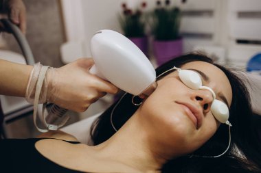 Elos epilasyon tüy çıkarma prosedürü bir kadının yüzünde. Güzellik uzmanı güzellik salonunda boynu lazerle gençleştiriyor. Yüz bakımı. Donanım ipl kozmetolojisi