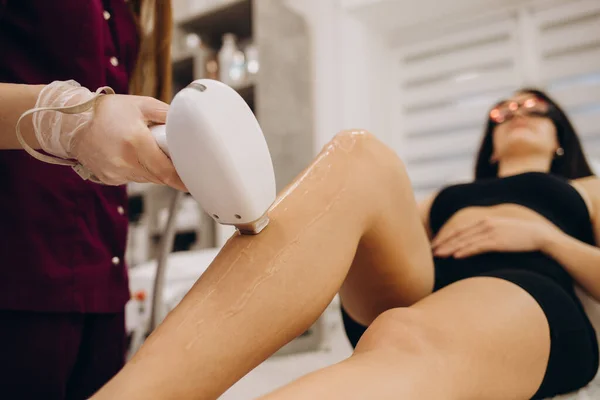 Laser epilation and cosmetology in beauty salon. Hair removal procedure. Laser epilation, cosmetology, spa, and hair removal concept. Beautiful woman getting hair removing on legs