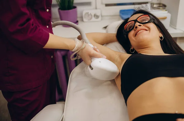 Laser epilation and cosmetology in beauty salon. Hair removal procedure. Laser epilation, cosmetology, spa, and hair removal concept. Beautiful brunette woman getting hair removing on underarm