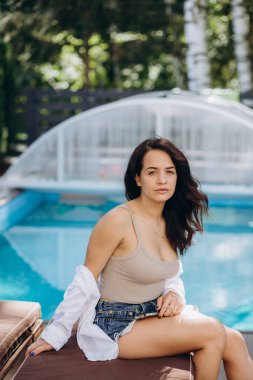 Havuz kenarında oturan genç bir kadın. Açık işyeri. Serbest yazar konsepti. İnternetten alışveriş. Tatil işi.