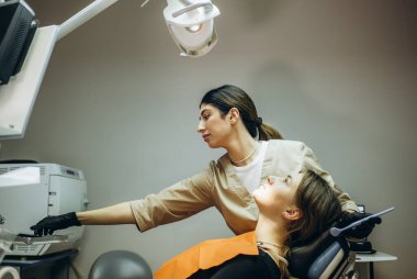 Dişçi sözlü muayene yapıyor. Güzel sabırlı kadın dişçi randevusuna geldi.