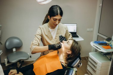 Dişçi sözlü muayene yapıyor. Güzel sabırlı kadın dişçi randevusuna geldi.