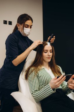 Genç bir kadın karanlık klinikte trikoloğu ziyaret ediyor.