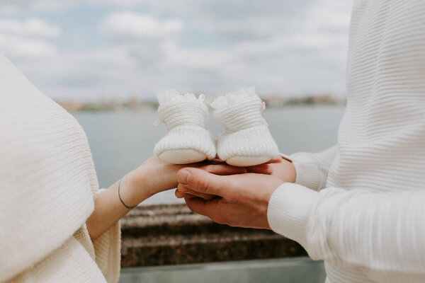 Husband and pregnant woman holding baby shoes, closeup