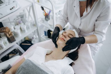 Sakin genç kadın güzellik salonunda yaşlanma karşıtı gençleştirme yordamı olmaya başladı. Onun yüzünü altında aracı holding Relax eller. Üstten Görünüm