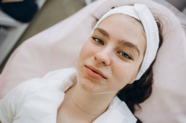 Genç kadın salonda yüz cilt temizliği. Retinol kabuğu fırça ile. Asit organik peeling.