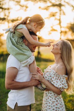 Mutlu yaz yürüyüşleri, anne, baba ve kızlar parkta yürüyor ve güzel doğanın tadını çıkarıyorlar..