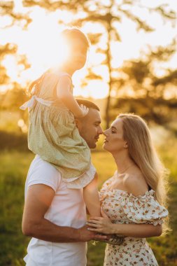 Happy family of three lying in the grass in autumn. Warm effect added.