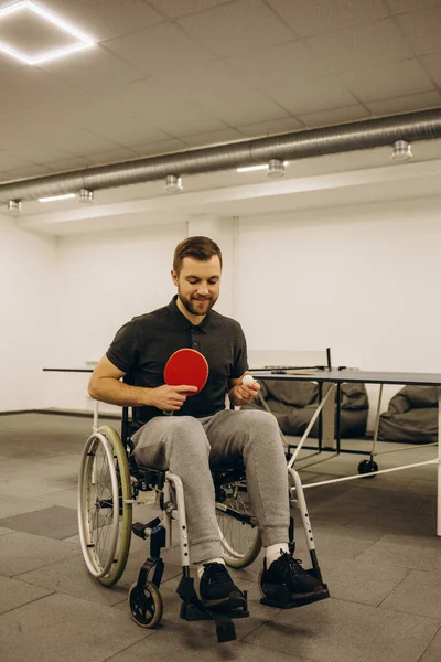 A man in a wheelchair plays table tennis