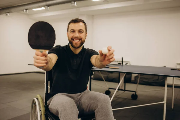 A man in a wheelchair plays table tennis