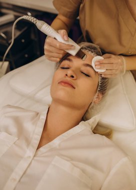 Ultrasound face therapy close-up. The cosmetologist makes the patient a face cleaning with an ultrasound apparatus in a cosmetology clinic.