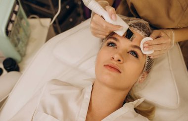 Ultrasound face therapy close-up. The cosmetologist makes the patient a face cleaning with an ultrasound apparatus in a cosmetology clinic.