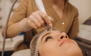 Beautician applying hydro gel mask on the young woman face, before laser treatment in beauty salon. Close up side view.