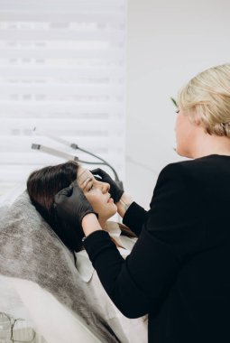 Woman in gloves making preparation to the brow permanent makeup with a ruler