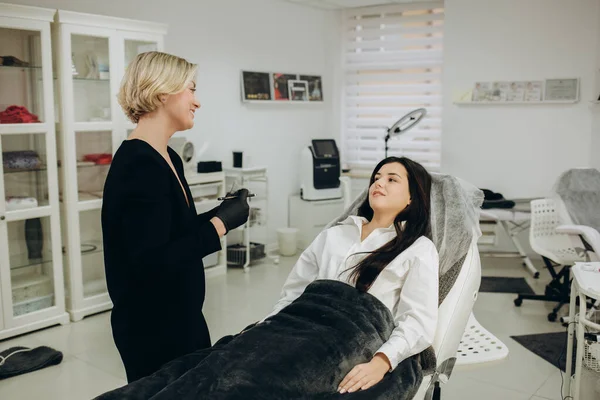 Eyebrow and lip tattooing room, cosmetologist and permanent make-up master. The master selects the desired color of the pigment for the lips and shows the options to the client. Beauty cosmetology