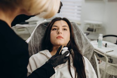 Kalıcı makyajdan önce profesyonel kaş haritalama işlemi sırasında genç bir kadın.