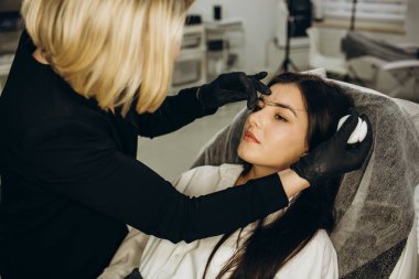 Kalıcı makyajdan önce profesyonel kaş haritalama işlemi sırasında genç bir kadın.