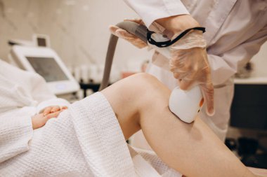 Efendimiz kızın bacaklarını lazer tüyü çıkarma prosedürü yapıyor.