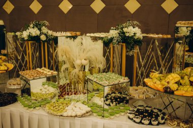 Wedding decorations. Reception. Buffet. Fruits and cheese on plates with bread in boxes. Food bar decorated by flowers and lanters.
