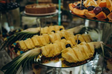 Wedding decorations. Reception. Buffet. Fruits and cheese on plates with bread in boxes. Food bar decorated by flowers and lanters.