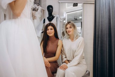 Gelinin butikte gelinlik giymesine yardım eden kadın.