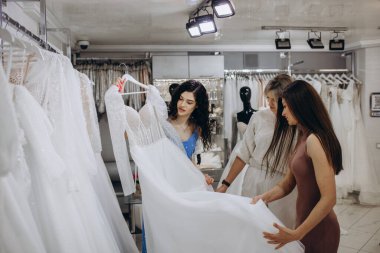 Three girlfriends - A Bride-To-Be and bridesmaid Trying On A Wedding dress