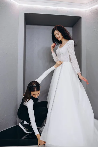 洋服店で仕立て屋の置く彼女の結婚式に花嫁を助けるドレスします — ストック写真