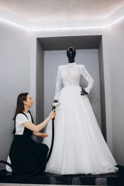 女性アイロン機でスタジオでウェディングドレスをアイロン 結婚式のコンセプト — ストック写真