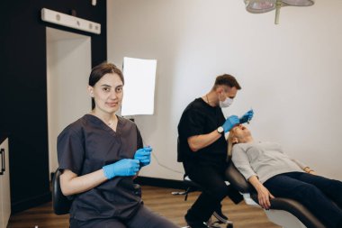 Yaşlı kadın ağız sağlığı kontrolü sırasında dişçi kabinesinde asistan sandalyeye oturuyor. Üst düzey kadın stomatoloji ofisinde tıp hemşiresiyle diş problemi hakkında konuşuyor..