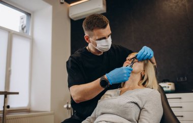 A plastic surgeon examines old eye wrinkles in an elderly woman. Clinic of modern plastic surgery