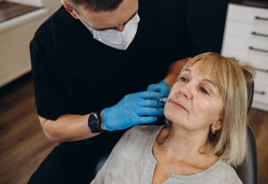 Güzellik, estetik cerrahi ve kozmetik kavramı - kadın kıdemli ve cerrah el ile mavi arka plan üzerinde şırınga